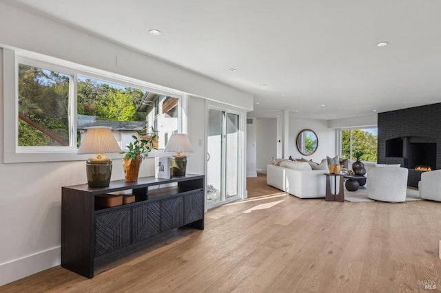 living room featuring a fireplace, recessed lighting, baseboards, and wood finished floors
