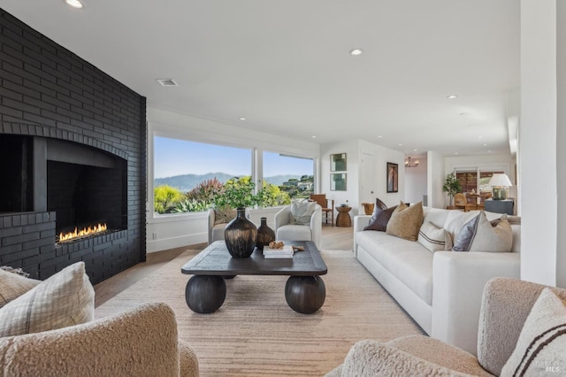 living area with visible vents, wood finished floors, a brick fireplace, and recessed lighting
