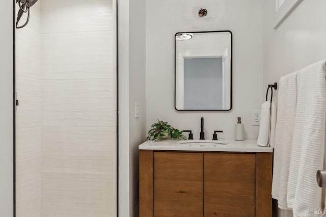 bathroom with tiled shower and vanity