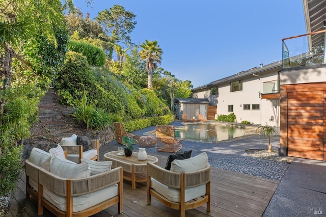 deck with an outdoor hangout area, an outbuilding, an outdoor pool, and a storage unit
