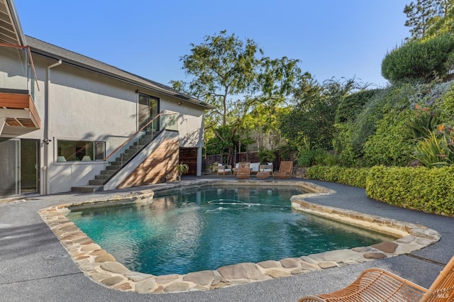 view of swimming pool featuring a patio area, fence, a fenced in pool, and stairs