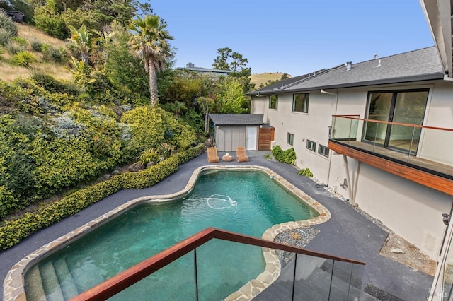 pool featuring an outbuilding, a patio area, and a storage unit