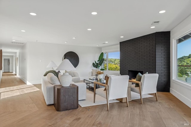 living area with a water view, a brick fireplace, light wood-type flooring, and recessed lighting