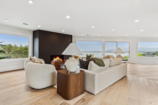 living area featuring light wood-type flooring, recessed lighting, a fireplace, and visible vents