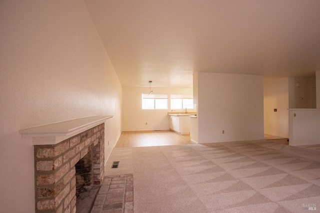unfurnished living room featuring visible vents, a brick fireplace, and carpet floors