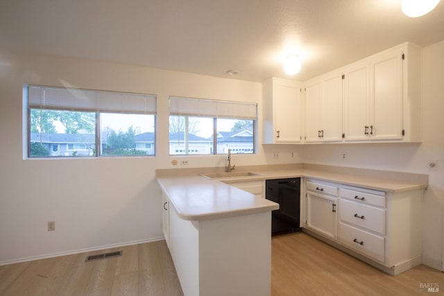 kitchen with light wood-style flooring, a peninsula, visible vents, dishwasher, and a sink