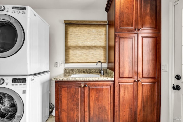 laundry room with stacked washer and clothes dryer, a sink, and cabinet space