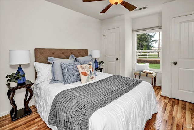bedroom with wood finished floors, visible vents, and baseboards