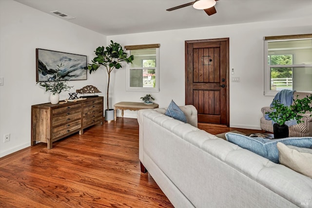 living area with baseboards, a ceiling fan, wood finished floors, and visible vents