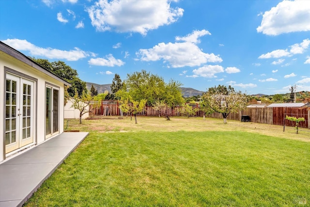 view of yard featuring a fenced backyard, french doors, and a mountain view