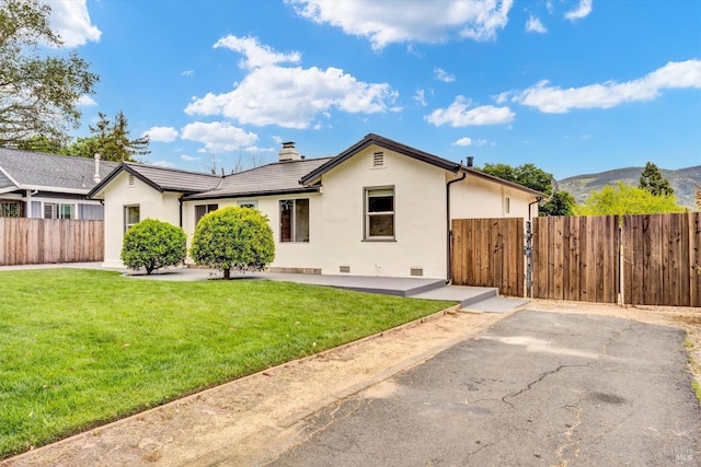 view of front of house featuring stucco siding, a front lawn, fence, and a mountain view