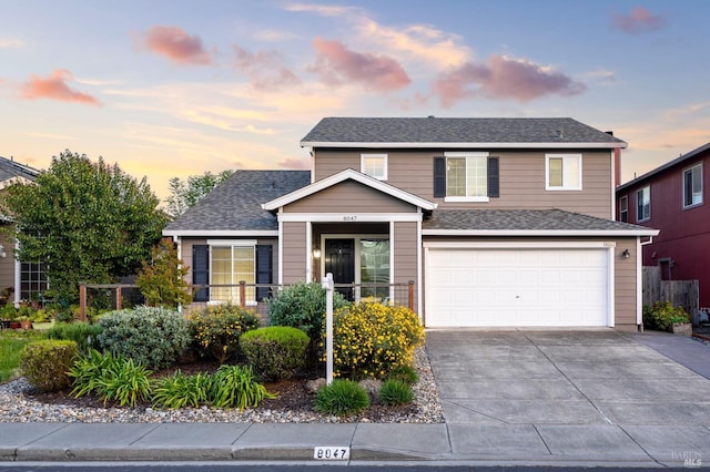 traditional-style home with a shingled roof, driveway, and an attached garage