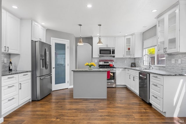 kitchen with a center island, a sink, appliances with stainless steel finishes, white cabinetry, and backsplash