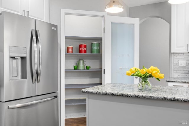 kitchen with light stone counters, white cabinetry, open shelves, stainless steel refrigerator with ice dispenser, and wood finished floors