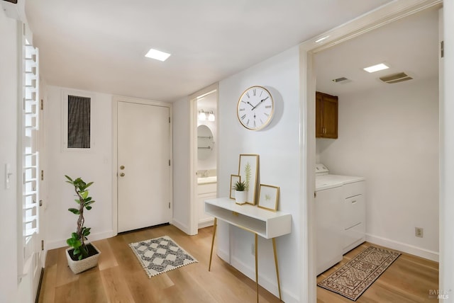 foyer entrance featuring baseboards, washer and clothes dryer, and light wood-type flooring