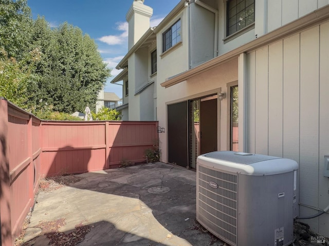 exterior space featuring a chimney, a fenced backyard, a patio, and central air condition unit