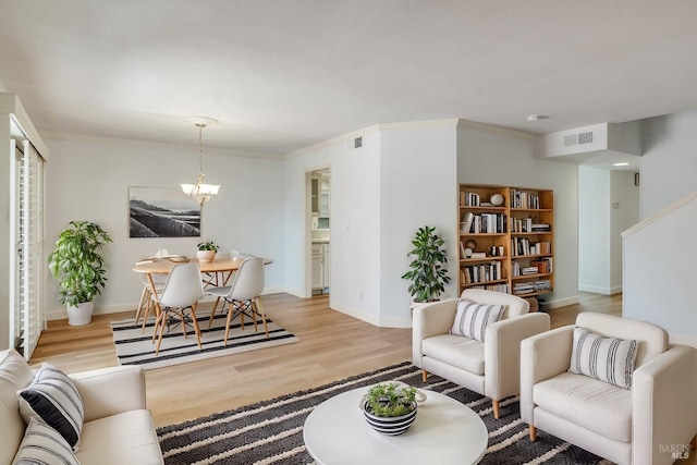 living room with visible vents, baseboards, light wood finished floors, and a chandelier