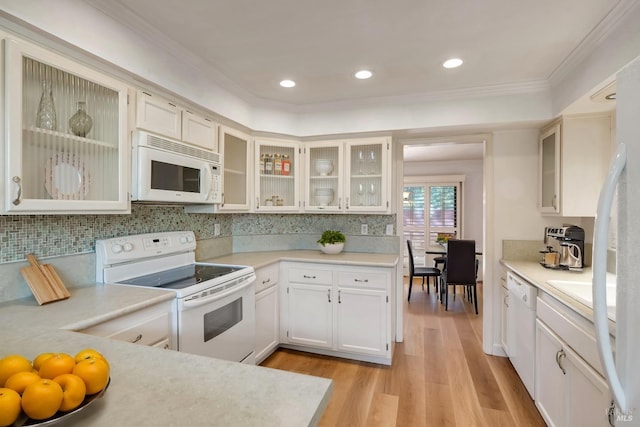 kitchen featuring light wood-style flooring, crown molding, light countertops, and white appliances