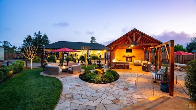 view of patio / terrace featuring an outdoor living space with a fireplace, a gazebo, and a fenced backyard