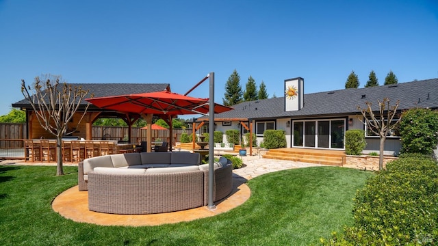 rear view of house featuring a patio, a shingled roof, outdoor dry bar, a lawn, and fence
