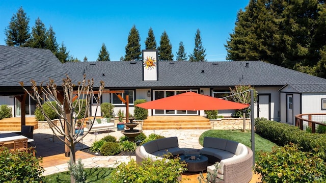 back of property featuring a patio area, a shingled roof, and an outdoor fire pit