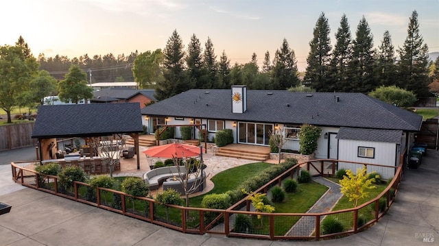 back of property featuring a chimney, fence, and a patio area