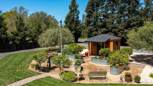 view of front of house featuring an outdoor structure, a front lawn, roof with shingles, and fence