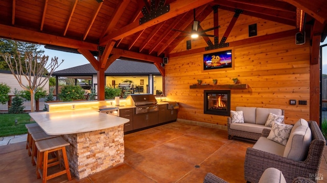 view of patio featuring outdoor dry bar, a gazebo, an outdoor living space with a fireplace, and grilling area