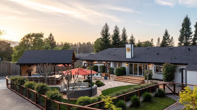 back of property at dusk featuring fence, a patio area, and outdoor lounge area