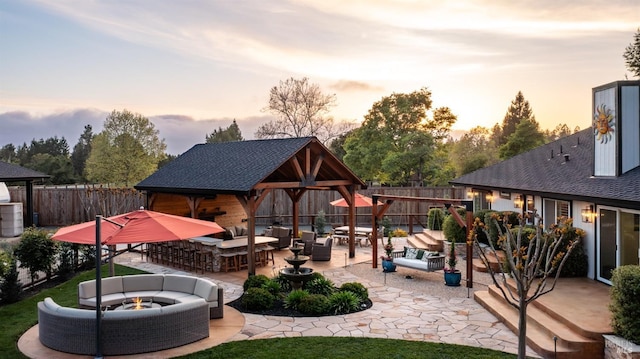 view of patio / terrace featuring an outdoor living space with a fire pit, a gazebo, an outbuilding, and a fenced backyard