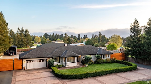 ranch-style house with fence, a front yard, driveway, and an attached garage