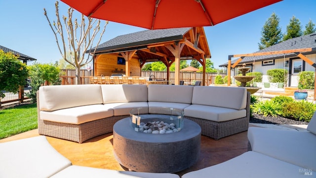 view of patio / terrace with fence, a gazebo, and an outdoor living space with a fire pit