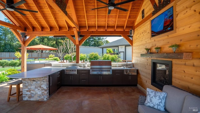 view of patio featuring exterior kitchen, area for grilling, outdoor wet bar, and ceiling fan
