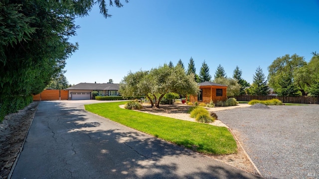 view of front facade featuring fence, a front lawn, and driveway