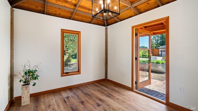 empty room featuring a chandelier, wooden ceiling, and baseboards