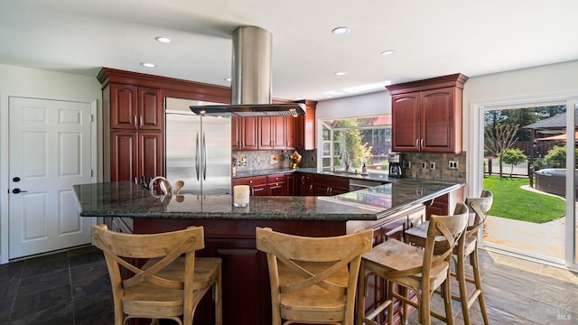 kitchen with dark brown cabinets, island range hood, appliances with stainless steel finishes, and decorative backsplash