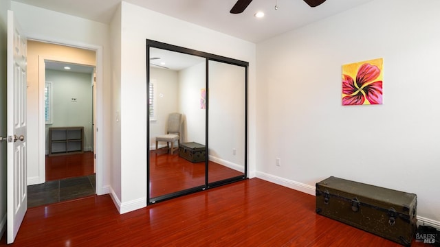 bedroom with wood finished floors, baseboards, a ceiling fan, and a closet