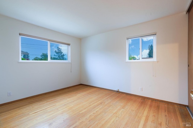 unfurnished room with light wood-style floors, baseboards, and a healthy amount of sunlight