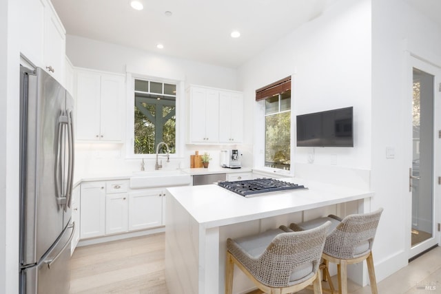 kitchen featuring a breakfast bar, recessed lighting, white cabinets, stainless steel appliances, and a sink