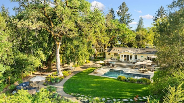 exterior space featuring a yard, a pool, a wooden deck, and a patio