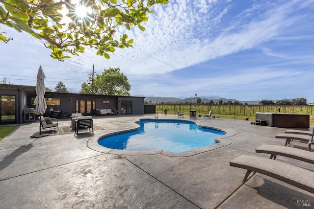 view of pool featuring a fenced in pool, a mountain view, fence, a patio area, and a jacuzzi