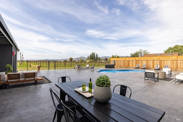 view of patio featuring a fenced backyard, a fenced in pool, outdoor dining area, and a mountain view