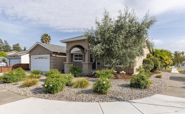 view of front of house featuring an attached garage, stucco siding, and fence