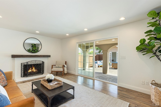 living room with recessed lighting, a brick fireplace, baseboards, and wood finished floors