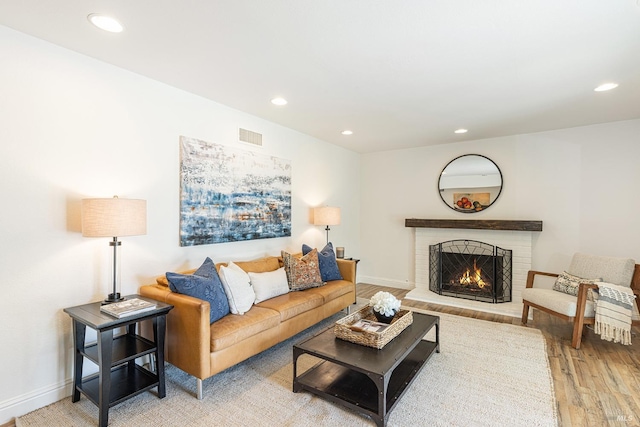 living area featuring a fireplace, visible vents, recessed lighting, light wood finished floors, and baseboards