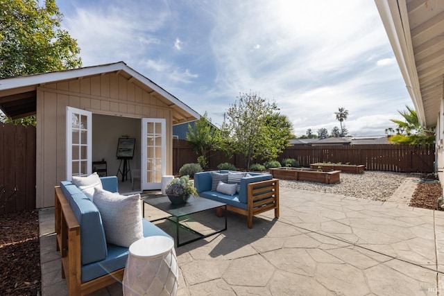 view of patio / terrace with an outdoor living space, an outdoor structure, a fenced backyard, and a vegetable garden