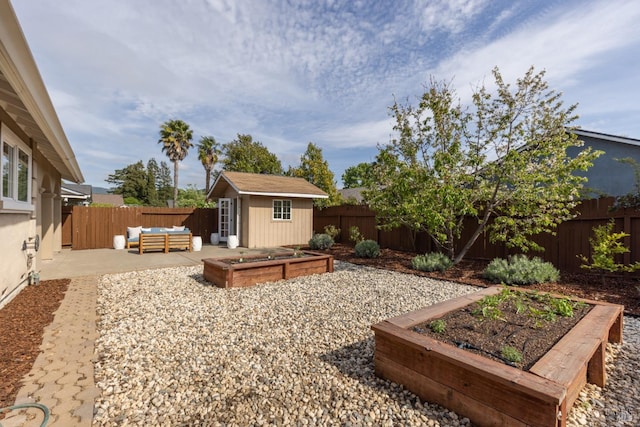 view of yard with an outbuilding, a garden, a fenced backyard, and a patio
