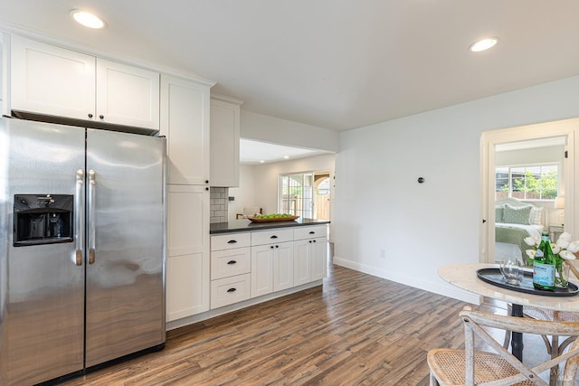 kitchen featuring white cabinetry, stainless steel refrigerator with ice dispenser, wood finished floors, dark countertops, and baseboards