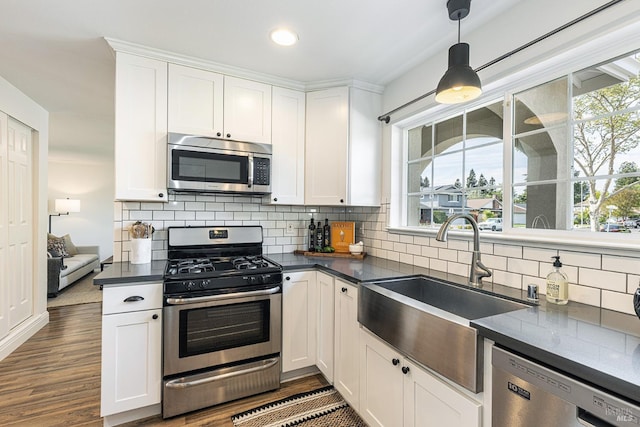 kitchen featuring a sink, dark countertops, appliances with stainless steel finishes, white cabinetry, and decorative backsplash