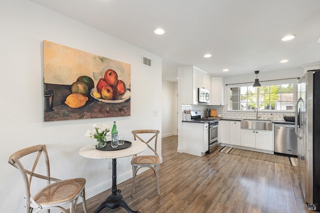 kitchen with visible vents, a sink, white cabinetry, wood finished floors, and stainless steel appliances